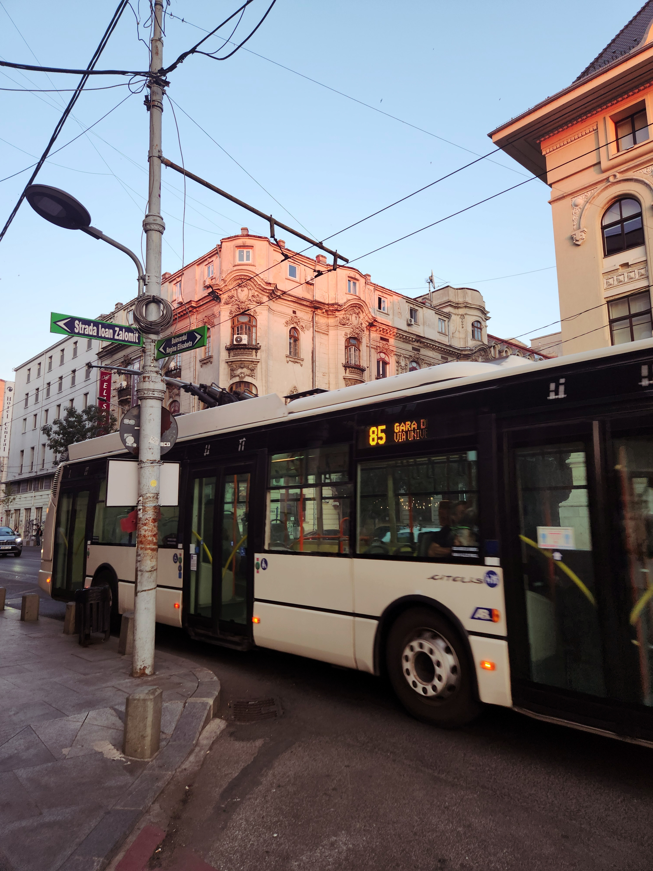 modern white trolleybus on a street in central Bucharest at sunset
