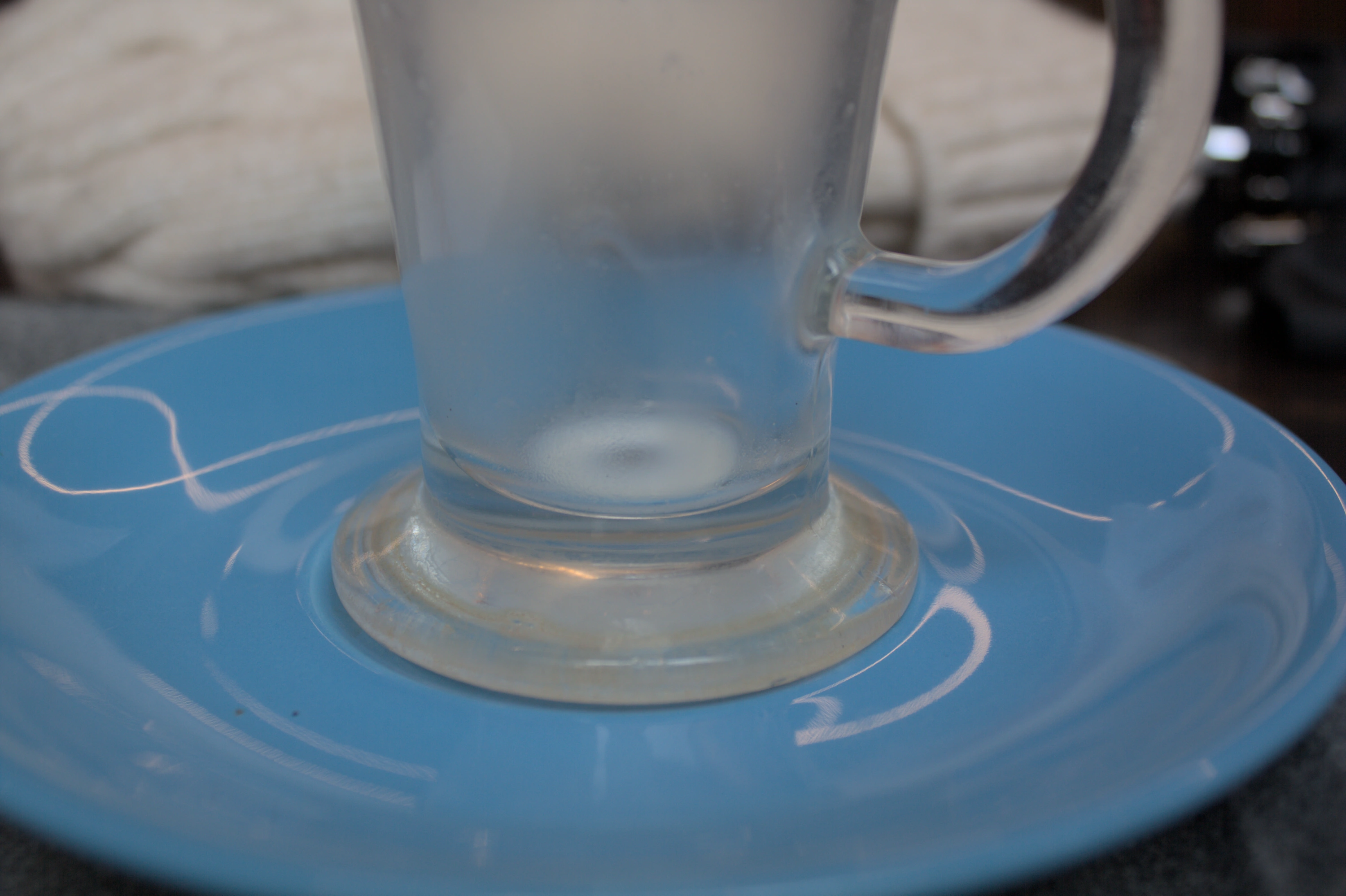 A blue saucer with the bottom of an empty glass cup