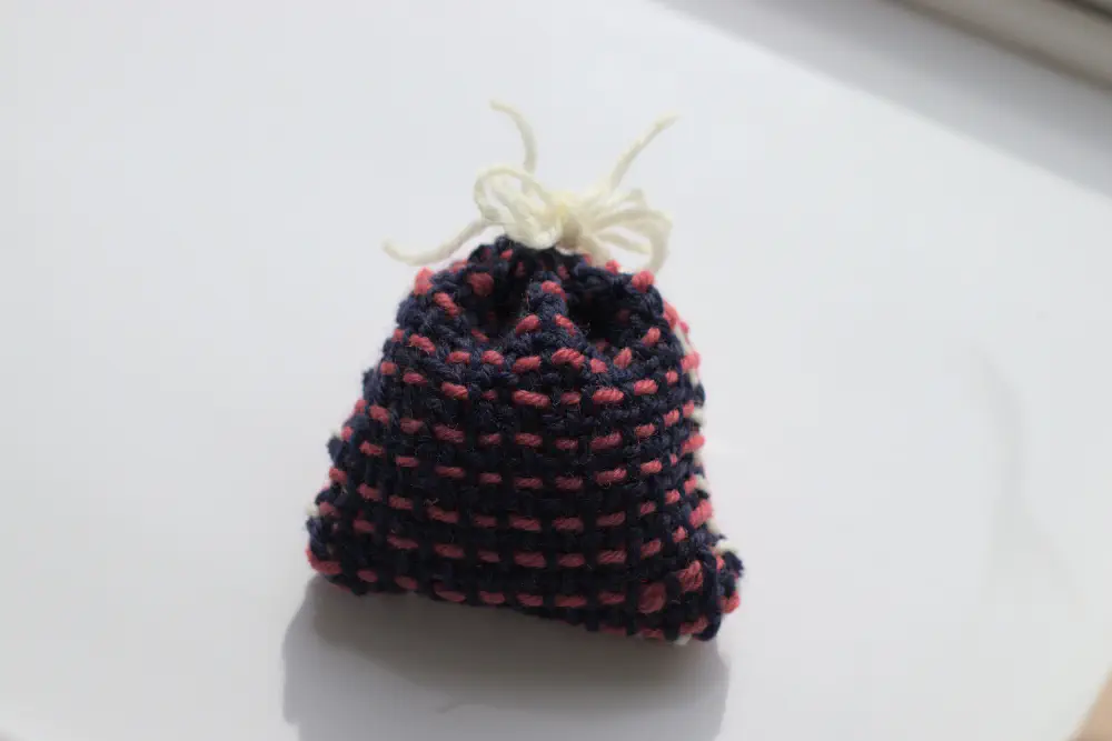 a tiny wool bag woven with navy background and pink dotted lines