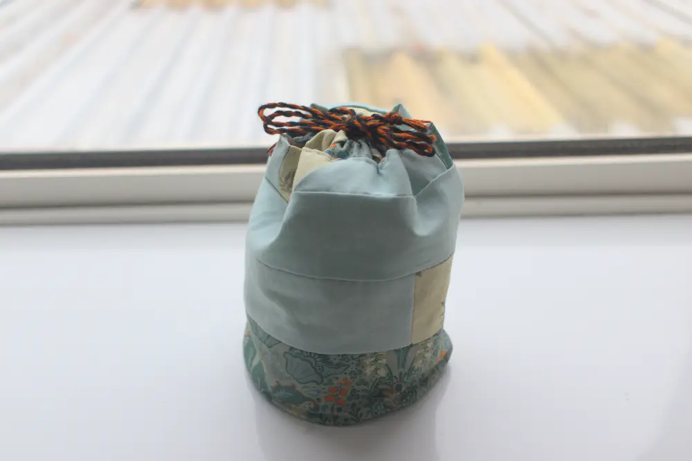 a round bottomed, tall drawstring bag mostly made of pale green fabric