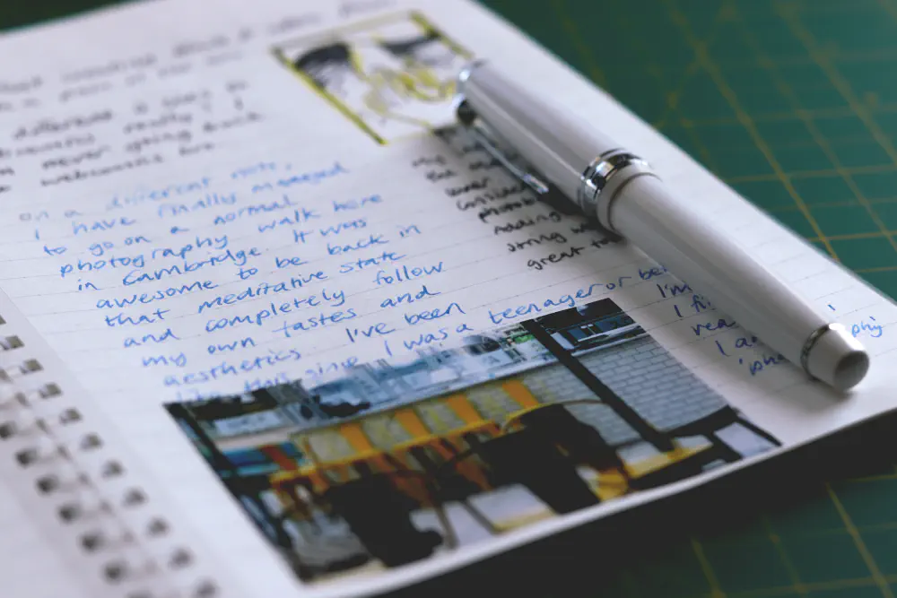 A journal with handwriting as well as a thumbnail drawing and a mini photo print stuck in